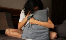 Ragazza sul letto che stringe un cuscino